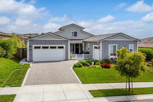 view of front of home featuring a garage, a front yard, and covered porch