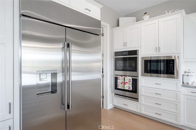 kitchen featuring white cabinetry, built in appliances, and light hardwood / wood-style floors