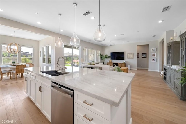 kitchen featuring white cabinetry, an island with sink, dishwasher, and sink