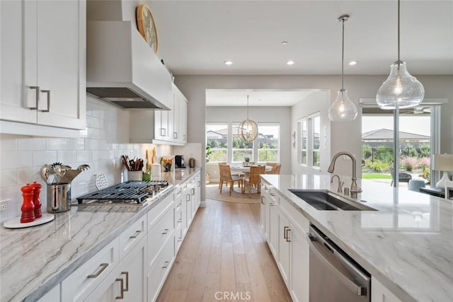 kitchen featuring sink, extractor fan, hanging light fixtures, stainless steel appliances, and white cabinets