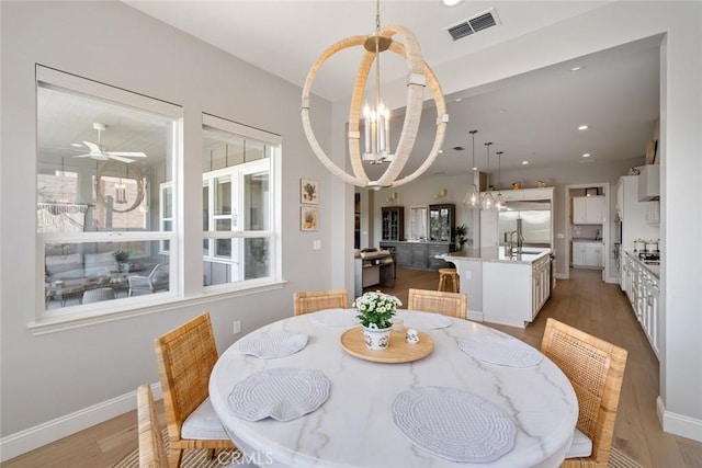 dining room with wood-type flooring, sink, and ceiling fan with notable chandelier