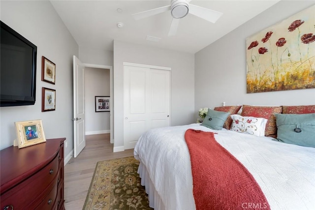 bedroom with light hardwood / wood-style flooring, ceiling fan, and a closet