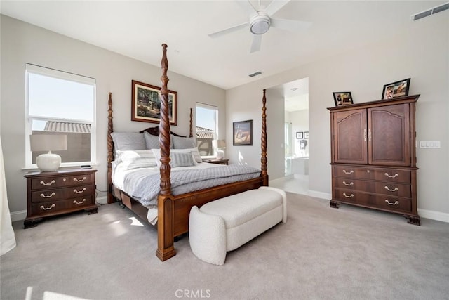 bedroom with ensuite bathroom, light carpet, and ceiling fan