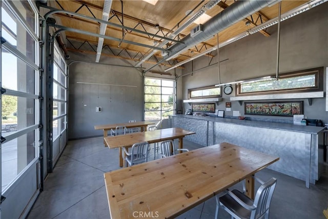 dining room with a towering ceiling and concrete floors