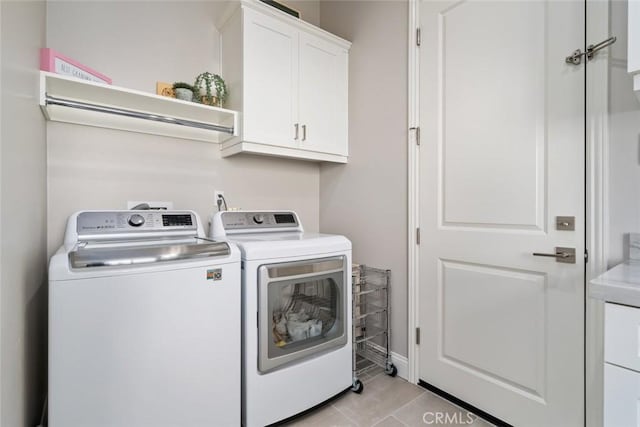 laundry area with cabinets, washer and dryer, and light tile patterned floors