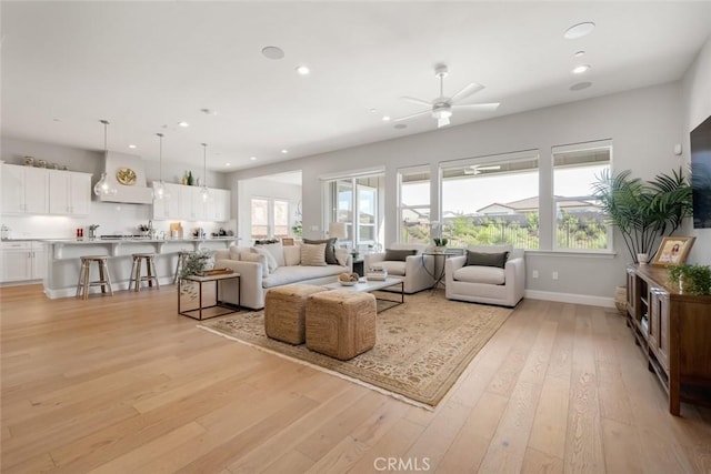 living room with ceiling fan and light hardwood / wood-style flooring