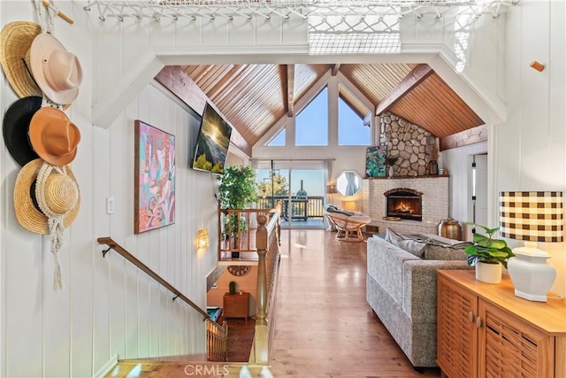 living area featuring a warm lit fireplace, high vaulted ceiling, and wood finished floors