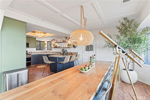 dining area with light wood-style floors and coffered ceiling