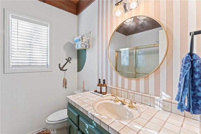 bathroom featuring toilet, wallpapered walls, and vanity