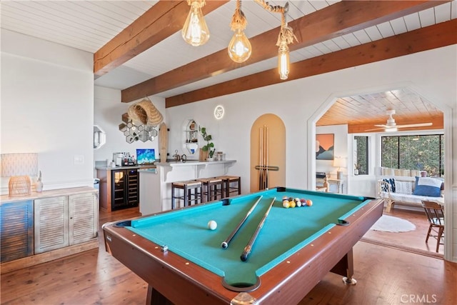 playroom featuring arched walkways, beverage cooler, wood finished floors, beam ceiling, and indoor wet bar