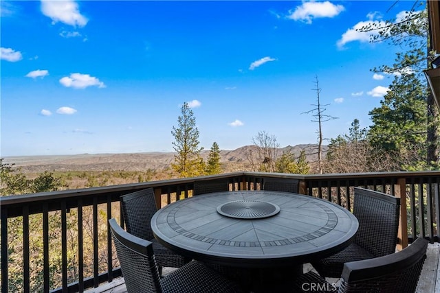 wooden deck with outdoor dining space and a mountain view