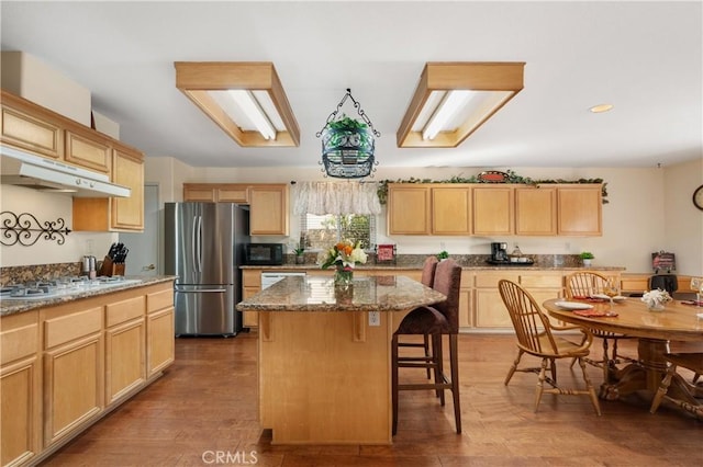 kitchen featuring stainless steel refrigerator, gas cooktop, a center island, and light brown cabinets