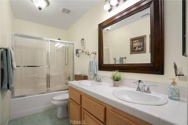 full bathroom with toilet, vanity, bath / shower combo with glass door, and tile patterned flooring