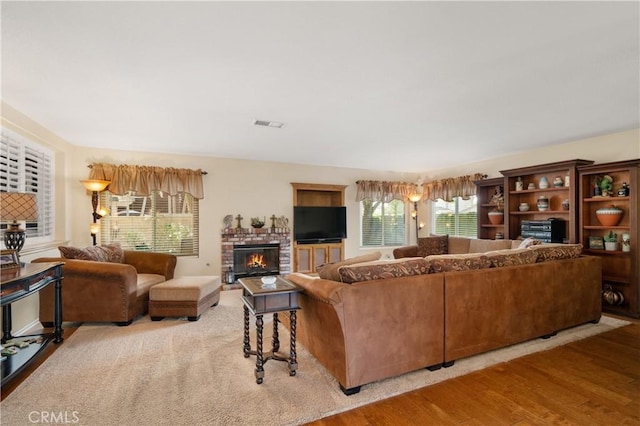 living room with a brick fireplace and light hardwood / wood-style floors