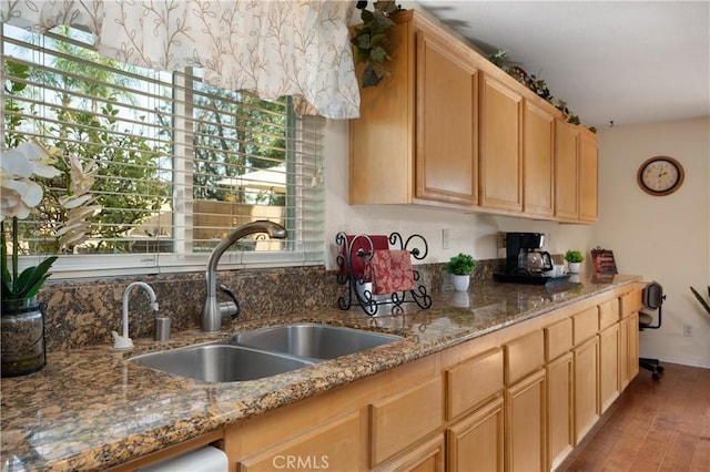 kitchen featuring sink, stainless steel dishwasher, light stone countertops, light brown cabinets, and light hardwood / wood-style flooring