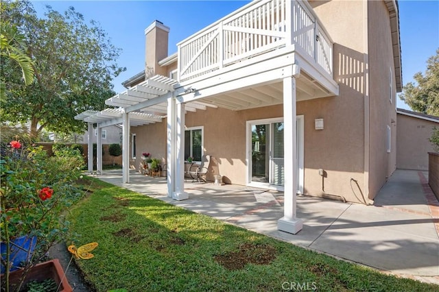 rear view of property featuring a balcony, a pergola, a patio area, and a lawn