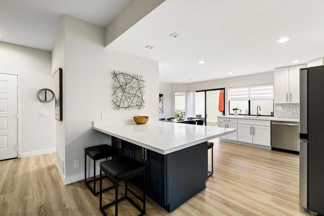 kitchen featuring a breakfast bar area, white cabinetry, tasteful backsplash, appliances with stainless steel finishes, and kitchen peninsula