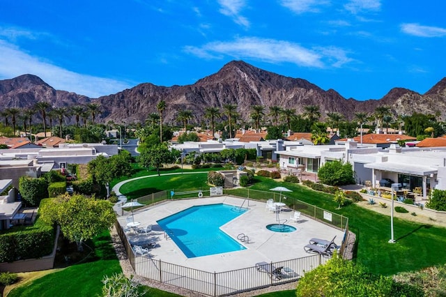 view of swimming pool with a community hot tub, a mountain view, a yard, and a patio area