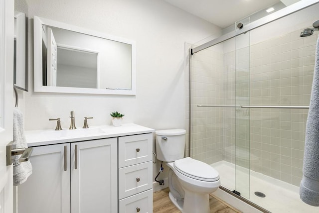 bathroom featuring an enclosed shower, wood-type flooring, vanity, and toilet