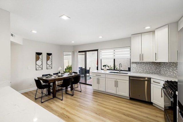 kitchen featuring black gas range oven, sink, white cabinetry, and stainless steel dishwasher