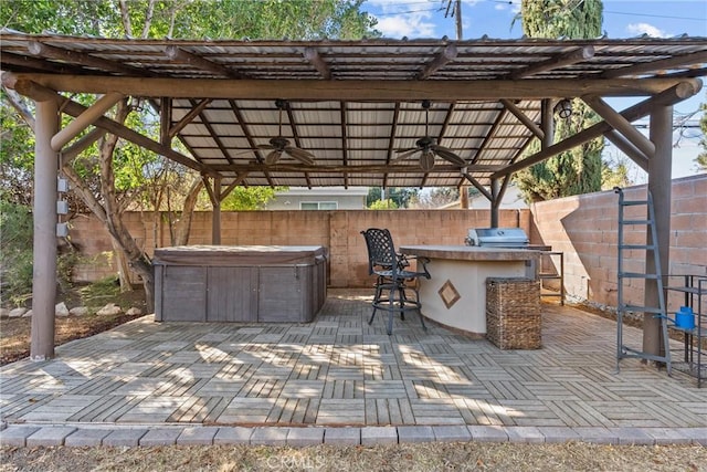 view of patio / terrace with an outdoor kitchen, area for grilling, a hot tub, an outdoor bar, and ceiling fan