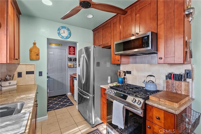 kitchen featuring light tile patterned flooring, decorative backsplash, ceiling fan, stainless steel appliances, and light stone countertops