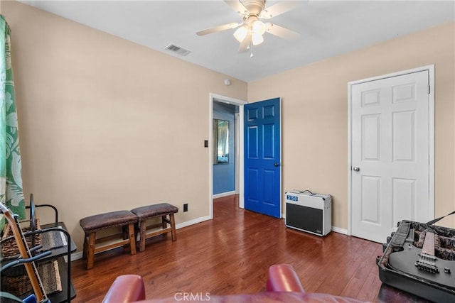 living area featuring ceiling fan and dark hardwood / wood-style flooring