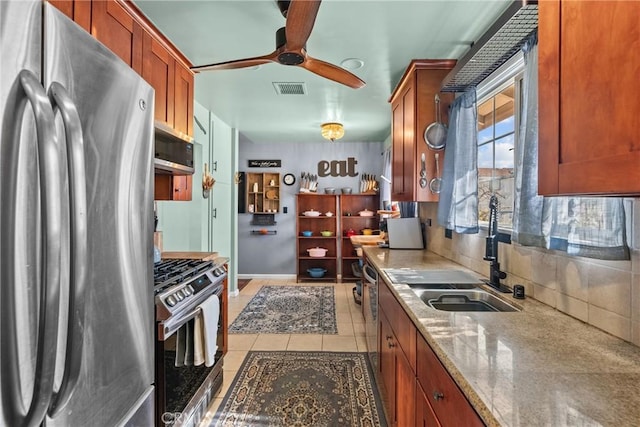 kitchen with light tile patterned flooring, sink, backsplash, stainless steel appliances, and light stone countertops