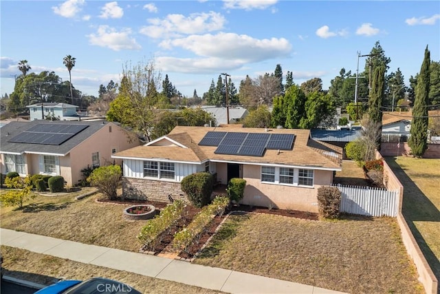 single story home with solar panels and an outdoor fire pit