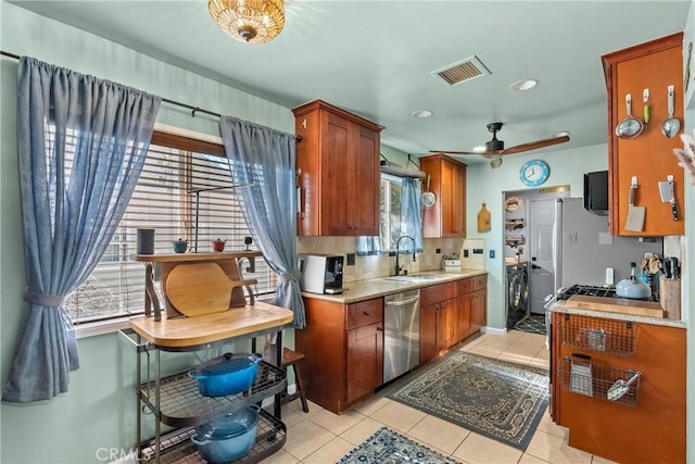 kitchen with appliances with stainless steel finishes, sink, light tile patterned floors, and separate washer and dryer