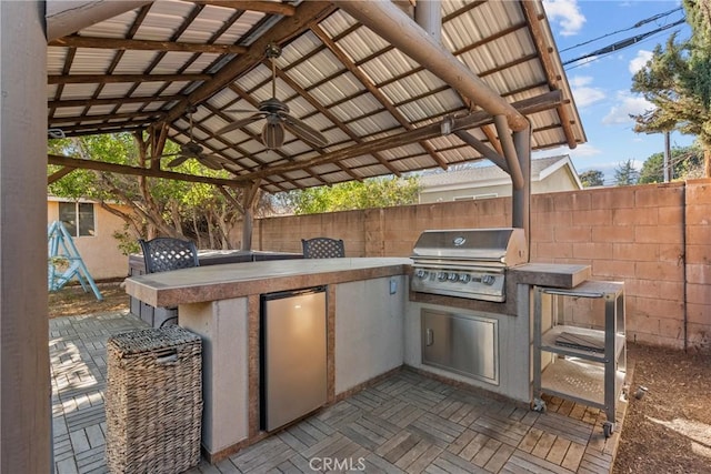 view of patio featuring a grill, a gazebo, ceiling fan, and an outdoor kitchen