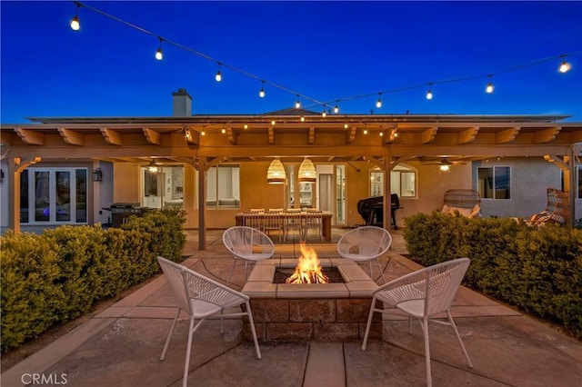 patio at night with an outdoor fire pit and a grill