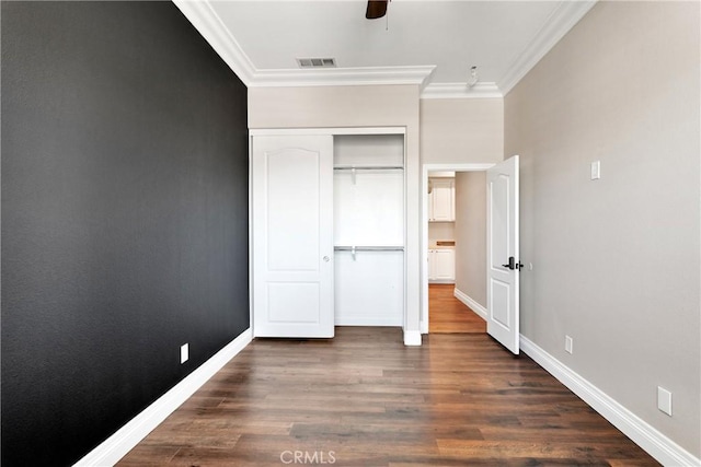 unfurnished bedroom featuring ceiling fan, ornamental molding, dark hardwood / wood-style flooring, and a closet