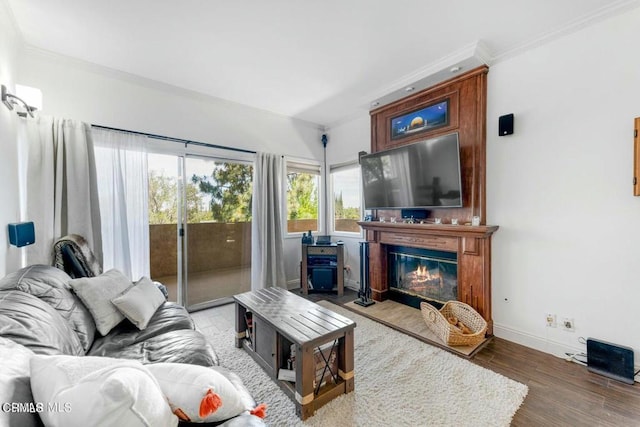 living area with crown molding, baseboards, wood finished floors, and a glass covered fireplace