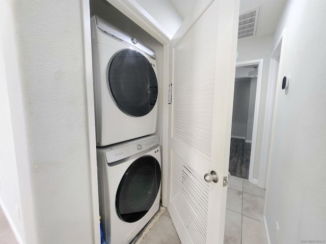 laundry room with stacked washer / dryer and light tile patterned flooring