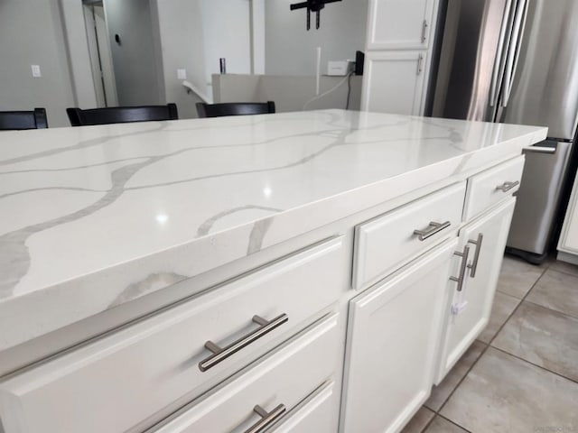 details featuring stainless steel refrigerator, light stone countertops, and white cabinets