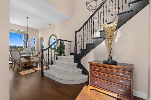 foyer with baseboards, stairway, wood finished floors, and a notable chandelier