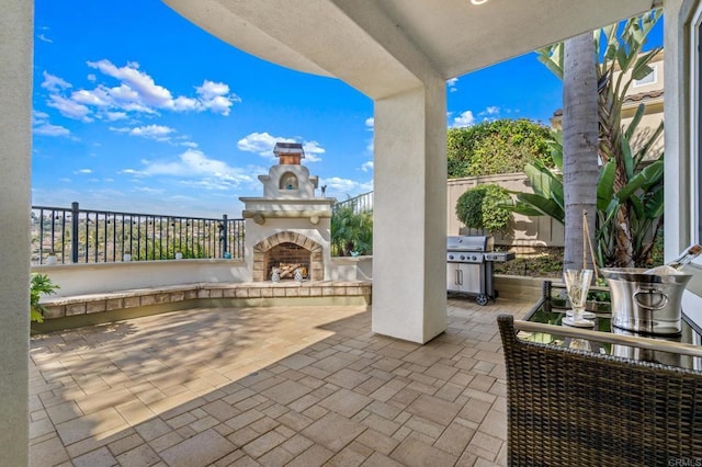 view of patio featuring a grill, fence, and an outdoor stone fireplace