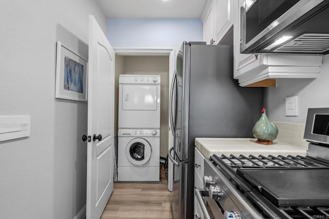 clothes washing area with light wood-style floors, stacked washer and clothes dryer, and laundry area