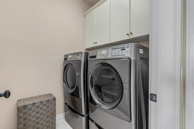 clothes washing area featuring washer and dryer, tile patterned flooring, and cabinet space