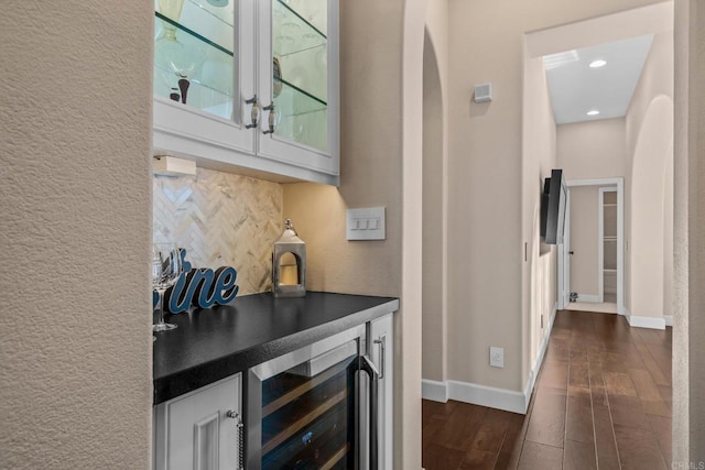 bar featuring a dry bar, baseboards, decorative backsplash, dark wood-style floors, and wine cooler