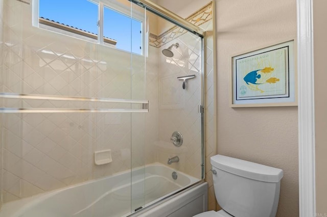 bathroom featuring a textured wall, shower / bath combination with glass door, and toilet