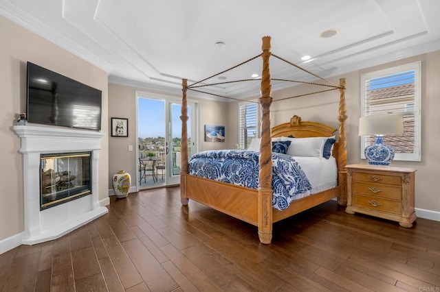 bedroom with access to exterior, dark wood finished floors, crown molding, and a glass covered fireplace