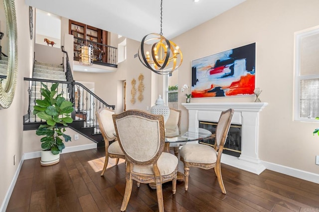 dining space featuring a glass covered fireplace, baseboards, stairway, and hardwood / wood-style floors