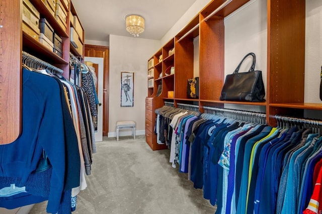 walk in closet with a chandelier and light carpet