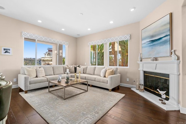 living room with recessed lighting, baseboards, a glass covered fireplace, and dark wood-style floors