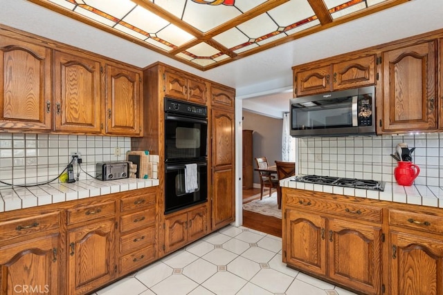 kitchen with stainless steel appliances, tile counters, and backsplash