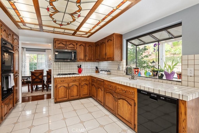 kitchen with sink, decorative backsplash, tile countertops, and black appliances