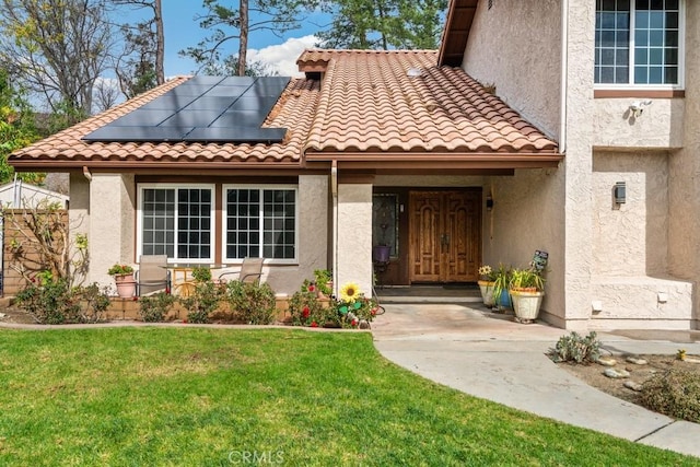 entrance to property featuring a lawn and solar panels