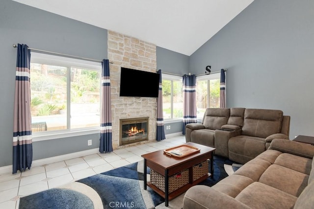 living room with a stone fireplace, light tile patterned floors, and high vaulted ceiling